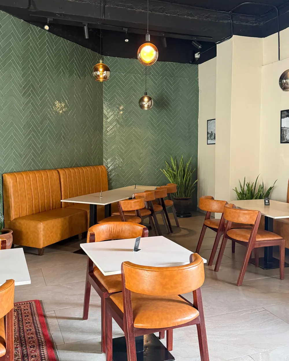 The dining room at Ayeyo: green herringbone tiles, caramel leather banquettes and pendant lights